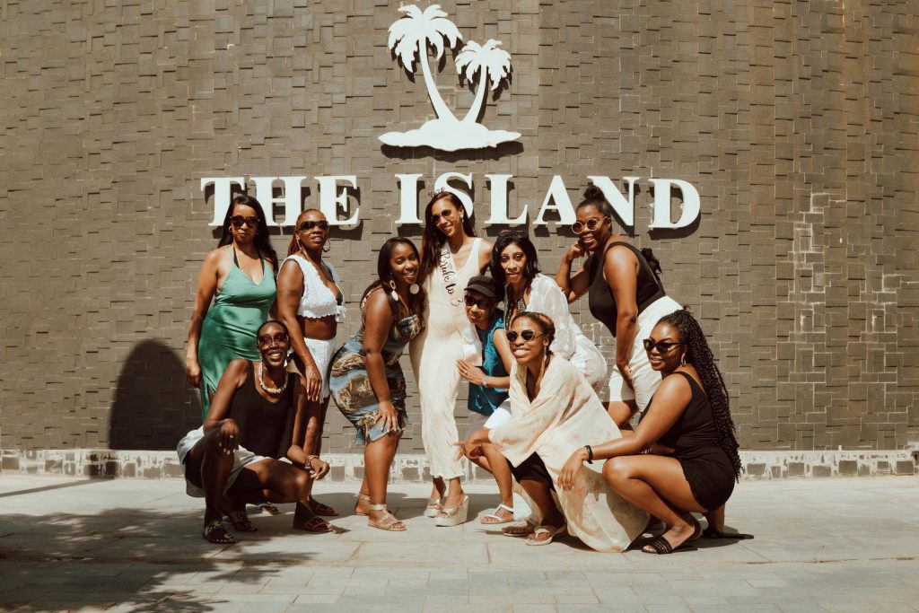 Group portrait of women in summer dresses in front of The Island sign